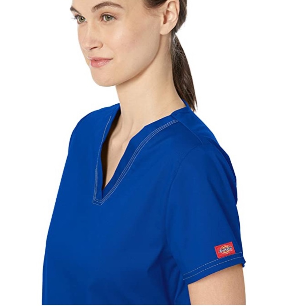 Dickies blue two pocket scrub top with tags.